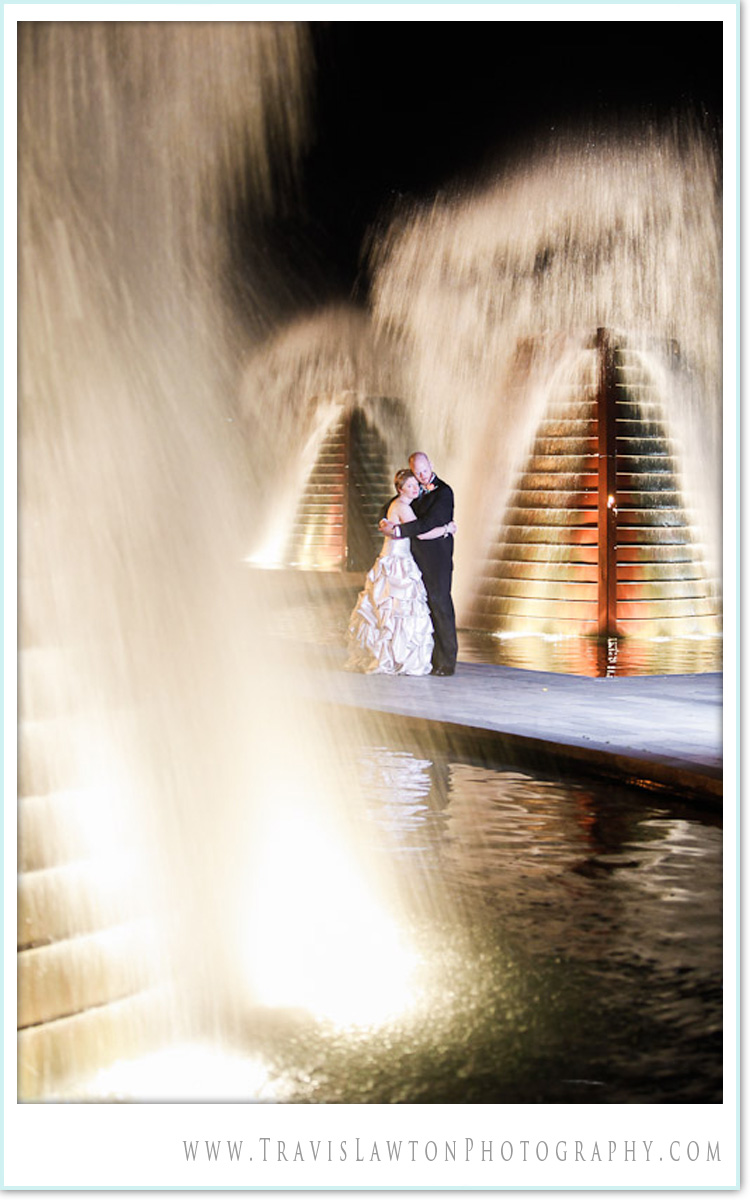 Beautiful image of the new bride and groom embracing while fountains explode all around them at Fountain Park in Bremerton across the Puget Sound From Seattle after their wedding